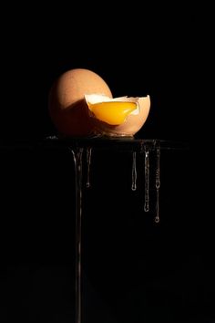 an egg sitting on top of a table next to a slice of fruit in the dark