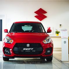 the front end of a red suzuki car in a showroom