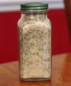 a jar filled with some kind of food on top of a wooden table next to a red wall