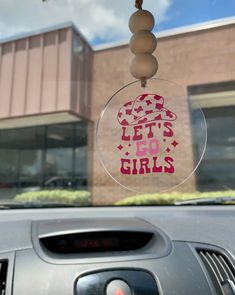 a car window with the words let's go girls on it and a hanging ornament