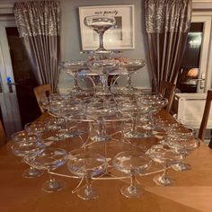 a table topped with lots of wine glasses on top of a wooden dining room table