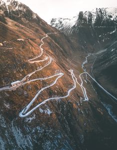 an aerial view of a winding road in the mountains with snow on the top and below