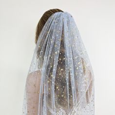 the back of a bride's head wearing a white veil with gold stars on it