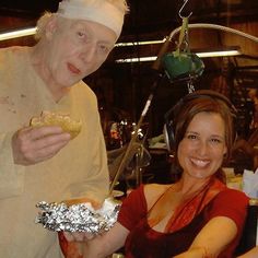 a man and woman sitting at a table with food in front of them, while wearing headphones