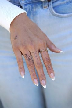 a woman's hand with tattoos on her left and right fingers, holding onto the other