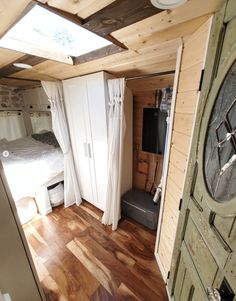 an open door leading to a bedroom with a bed in the corner and wooden floors