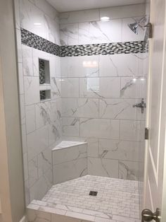 a walk in shower sitting next to a white wall and floor covered in marble tiles