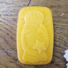 a close up of a yellow soap with a cat on it's face in the shape of a rectangle