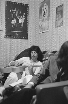 black and white photograph of two people sitting on a couch in a room with posters