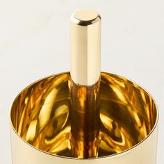 a gold colored metal container with a silver top and round base on the bottom, holding an empty bottle