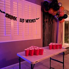 a party table with red cups and balloons