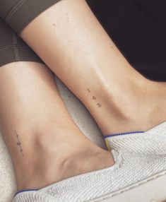 two people with matching tattoos on their feet sitting next to each other and one has the word love written on it