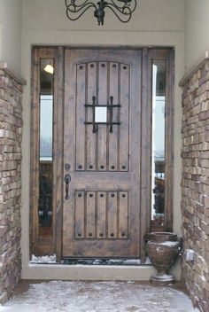 a large wooden door in front of a brick building with a chandelier hanging from the ceiling