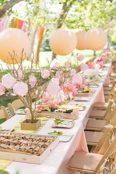 the table is set up with pink flowers and paper lanterns on it for an outdoor bridal