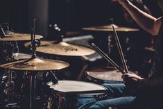 a man is playing drums while sitting in front of the drum set and holding his hands up