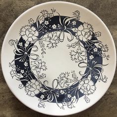 a black and white plate with flowers on it sitting on a table next to a wall