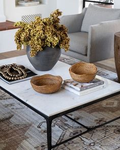 a coffee table with two bowls on it and a plant in the middle, sitting next to a couch