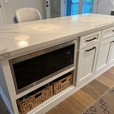 a white kitchen island with two baskets under the top and an oven on one side