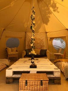 the inside of a large tent with tables and chairs in it, next to a wicker coffee table