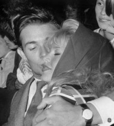 an old photo of a woman hugging a man's head in front of other people