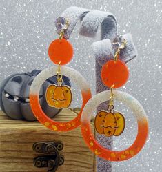 White and orange resin Halloween pumpkin earrings with holographic glitters and Jack O'Lantern charms The perfect pair of pendant earrings for Halloween night! They are entirely made in resin and glass pigments, cast in premium silicone molds. Each one of them is one of a kind since I mix resin with pigments for every single pair of earrings. Nickel-free studs with beautiful faceted crystal rhinestones and beautiful UV resin spooky Jack O'Lantern charms. Measures: approx. 7 cm (please see pictur Orange Resin Jewelry For Party, Spooky Orange Halloween Jewelry, Orange Novelty Halloween Jewelry, Pumpkin Earrings, Holographic Glitter, Halloween Night, Uv Resin, Faceted Crystal, Pendant Earrings