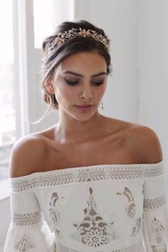 a woman wearing a white dress with a tiara on her head and looking down