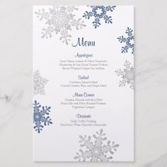 a snowflake menu card with blue and silver foil on the front, sitting on top of a marble surface