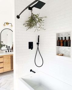 a bathroom with white brick walls and black faucet in the shower, surrounded by greenery