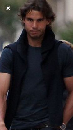 a man walking down the street with his hands in his pockets and wearing a black shirt