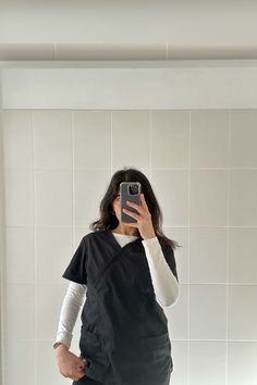 a woman taking a selfie with her cell phone in a bathroom mirror while wearing an apron