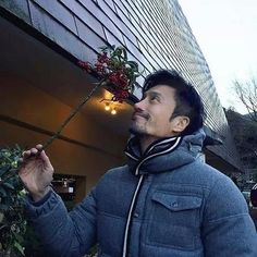 a man standing in front of a tall building with a fake flower hanging from it's side