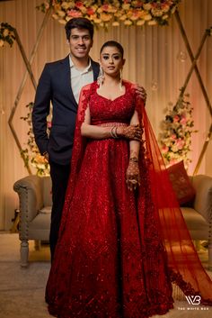 two people standing next to each other wearing red outfits