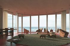 a living room filled with lots of furniture and large windows overlooking the ocean in front of it