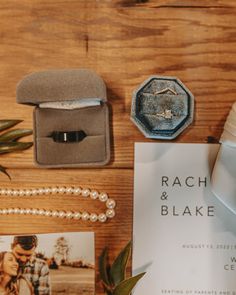 wedding rings, ring box and other items laid out on a wooden table next to each other