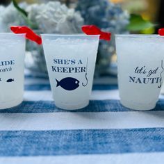 three shot glasses sitting on top of a blue and white table cloth with red bows