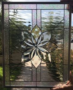 a hand holding up a stained glass window with a flower design on the bottom and sides