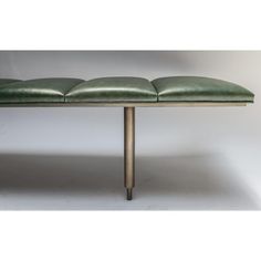 a green leather bench sitting on top of a metal frame table with four seats and two legs