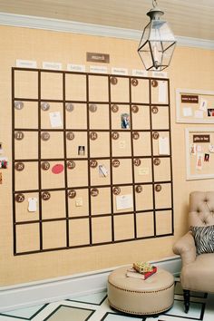 a living room with a chair, ottoman and calendar on the wall above it's coffee table