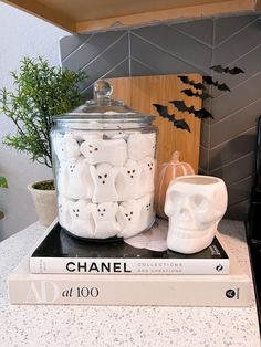 there is a jar with skulls on it next to a pair of glasses and a book