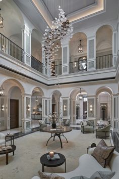 a large living room with high ceilings and chandeliers hanging from the rafters