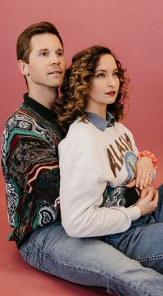 a man sitting next to a woman on the floor with her arms around her chest