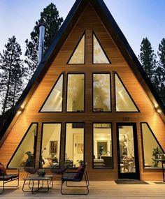 a - frame house with large windows and lots of seating on the front deck at night