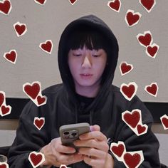 a person wearing a hoodie looking at a cell phone with hearts drawn on it