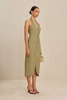 A halter suiting dress with various spherical, gold-toned hardware and embroidered contrast stitching at the front and back seams. — Rounded hem — Side zipper — Elastic halter neck — Shiny brass button details Halter Neck Dress Casual, Diy Wedding Dress, Boutique Ideas, Wedding Dress Patterns, Halter Neck Dress, Linen Fashion, Minimalist Dresses, Fashion 2024, Cult Gaia