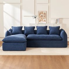 a blue sectional sofa sitting on top of a hard wood floor next to a white wall