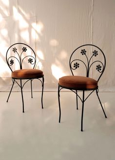 two chairs sitting next to each other in front of a white wall