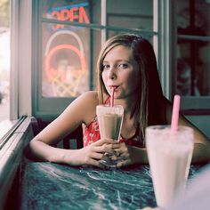 a woman sitting at a table with a drink