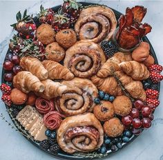 a platter filled with croissants, berries, and other food items