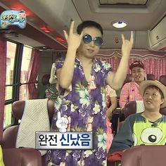 a man in a flowered dress waves to the camera while standing on a bus