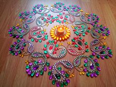 an assortment of colorful beads on a wooden floor with a candle in the center and other decorations around it